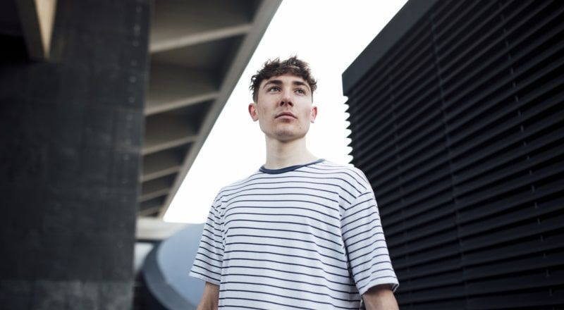 Illustrative image of a person using a laptop while playing with a fidget spinner on a wooden table.