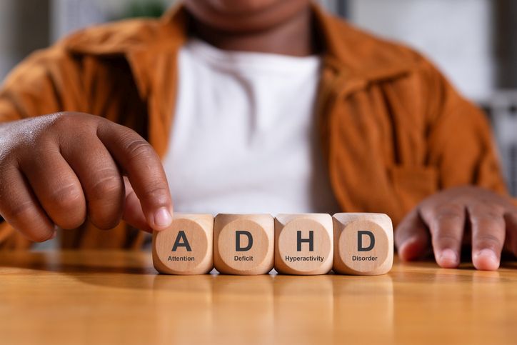 Illustrative image of a seated person with a close-up focus on their hands, one touching the first of four wooden blocks labelled