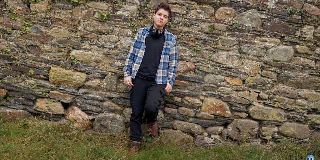 Video thumbnail of a person wearing headphones looking off into the distance in an outdoor setting.