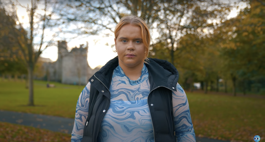 Video thumbnail of a person looking directly into the camera against a stone wall background.