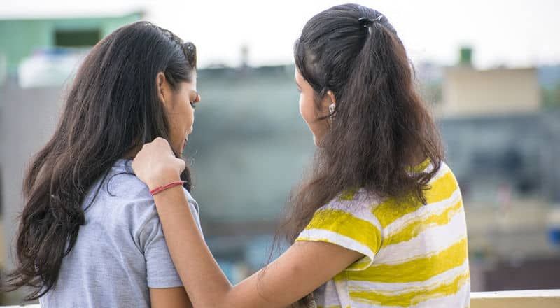 Illustrated image of a person placing a supportive hand on the shoulder of another person.