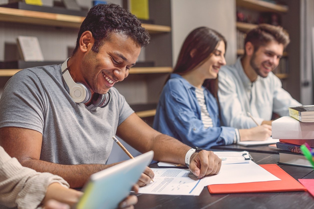 Illustrative image of three smiling people sitting together while studying.