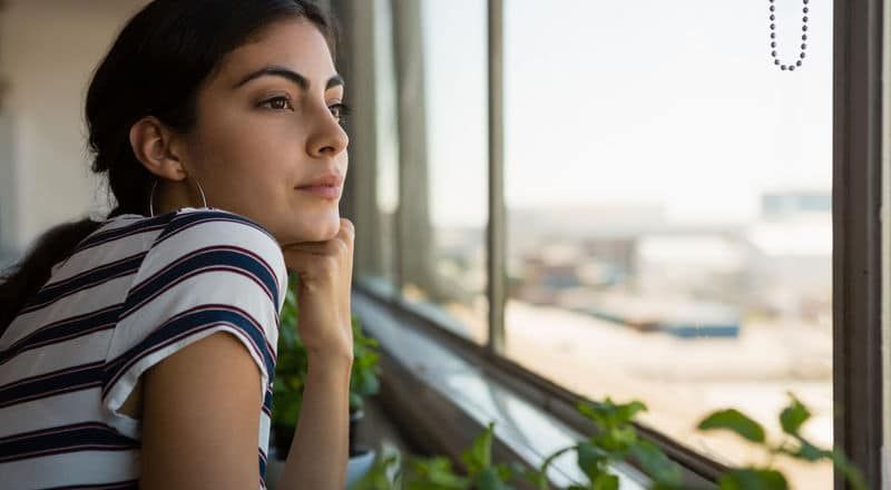 Illustrative image of a person gazing dreamily out a window.