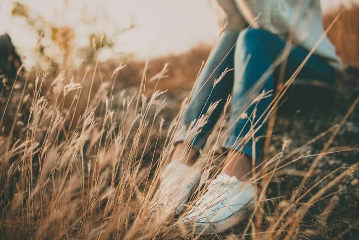 Illustrative image of a person sitting on a rock in a field.