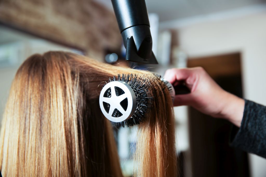 Illustrative image of a person blowdrying someone's hair using a radial brush.