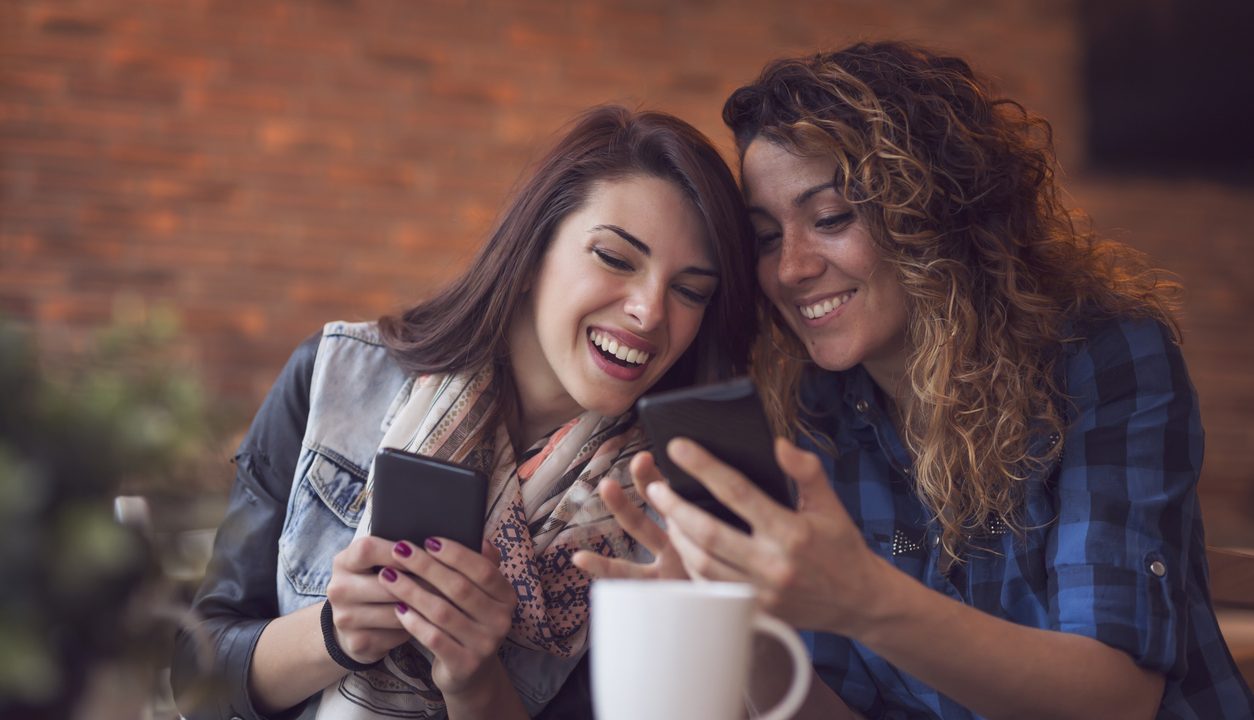Illustrative image of two friends looking at a phone.