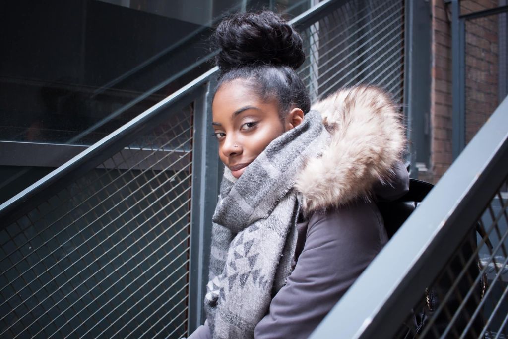 Illustrative image of a person sitting outside on steps, looking directly at the camera.