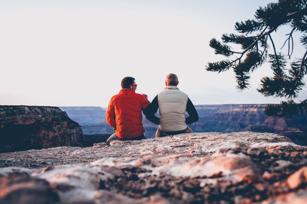 Illustrative close-up image of a person comforting a friend on a sofa in a living room.
