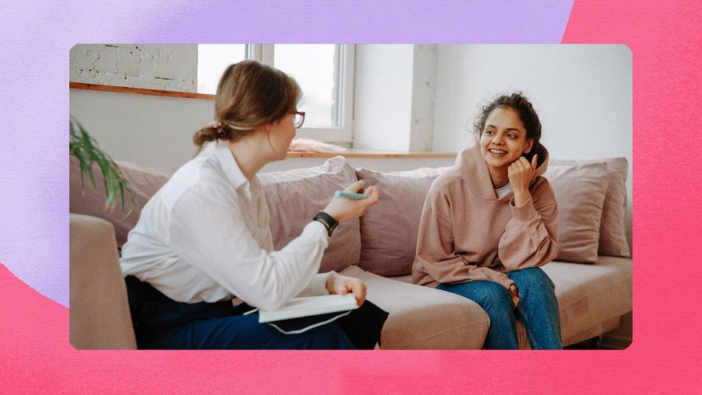 Illustrative image of two smiling people conversing on a couch, one person holding a notepad.