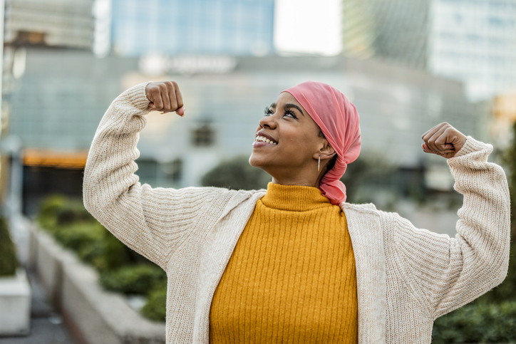 Illustrative image of a person smiling and raising both fists to celebrate their own strength.