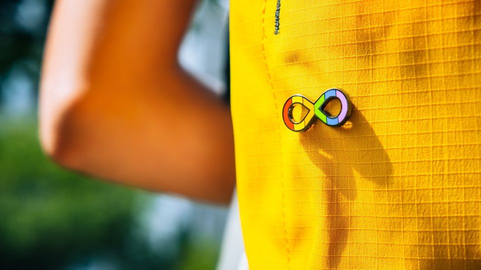 Illustrated image of a person wearing a colourful autism spectrum logo badge.