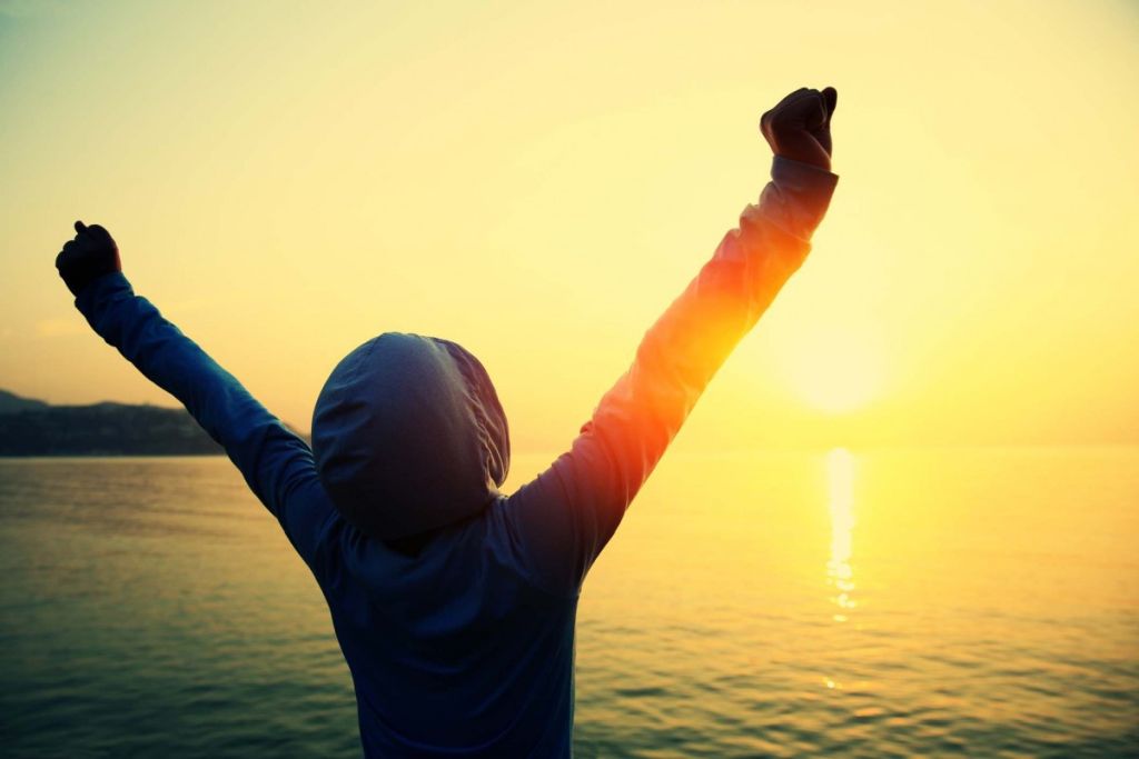 Illustrative image of a person smiling outside with their hair blowing in the wind.