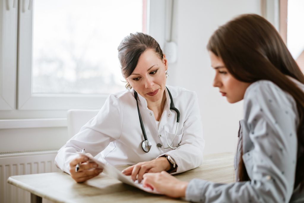 Illustrative image of a person with a stethoscope pointing to a sheet of paper while another person looks intently at the sheet.