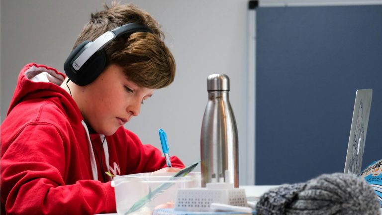 boy with headphones writing in journal