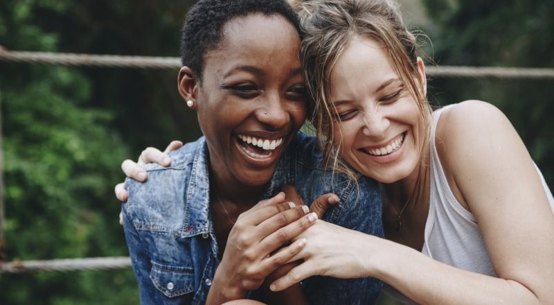 Illustrative image of two people embracing and laughing outside.