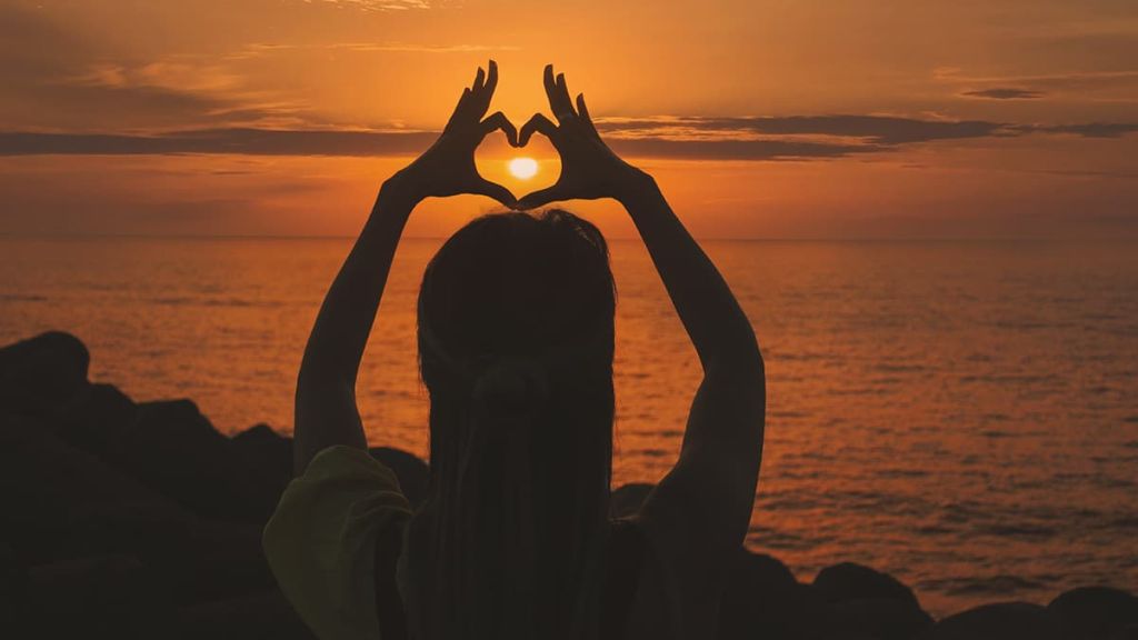 Illustrative image of a person standing mindfully in nature with arms outstretched, eyes closed, and head tilted back slightly. 