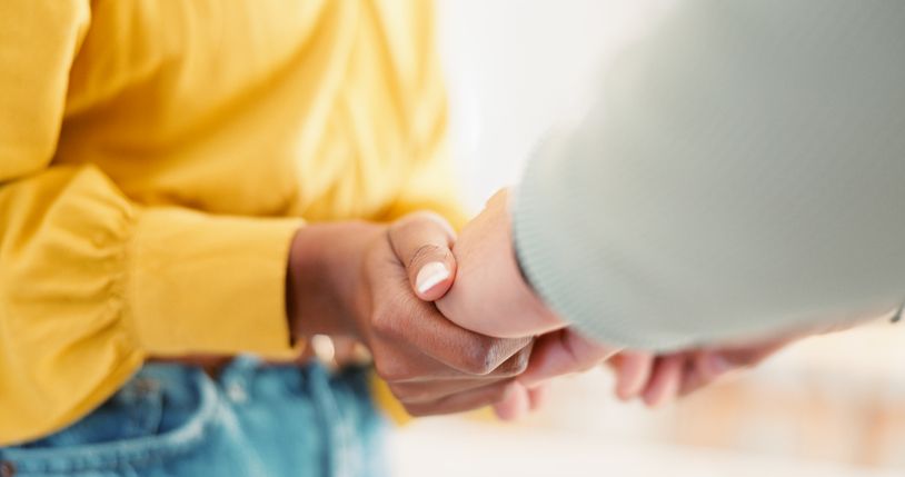 Illustrative image of a person holding another person's hands.