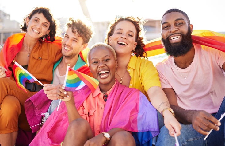 Illustrative image of a group of friends smiling and waving the rainbow flag.