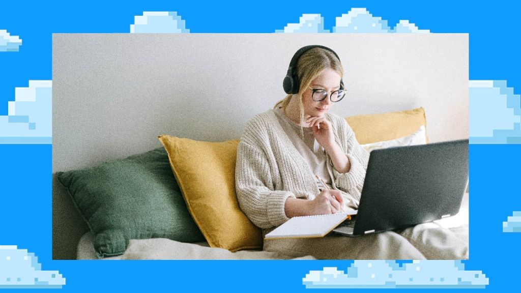 Illustrative image of a person sitting comfortably, propped up by cushions, writing in a notepad with a laptop balanced on their knees.