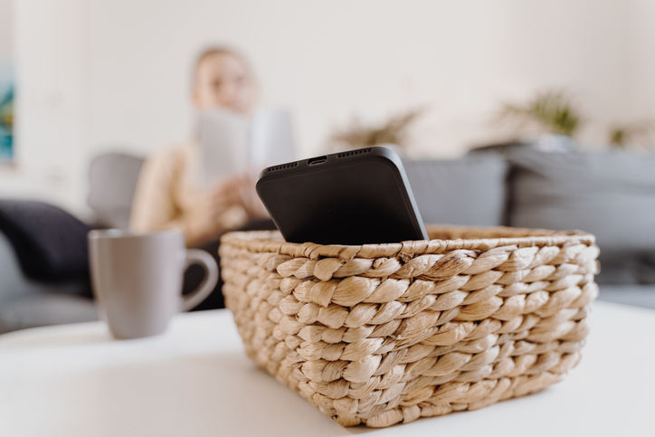 Illustrative image of a person reading while their phone is set aside in a basket.