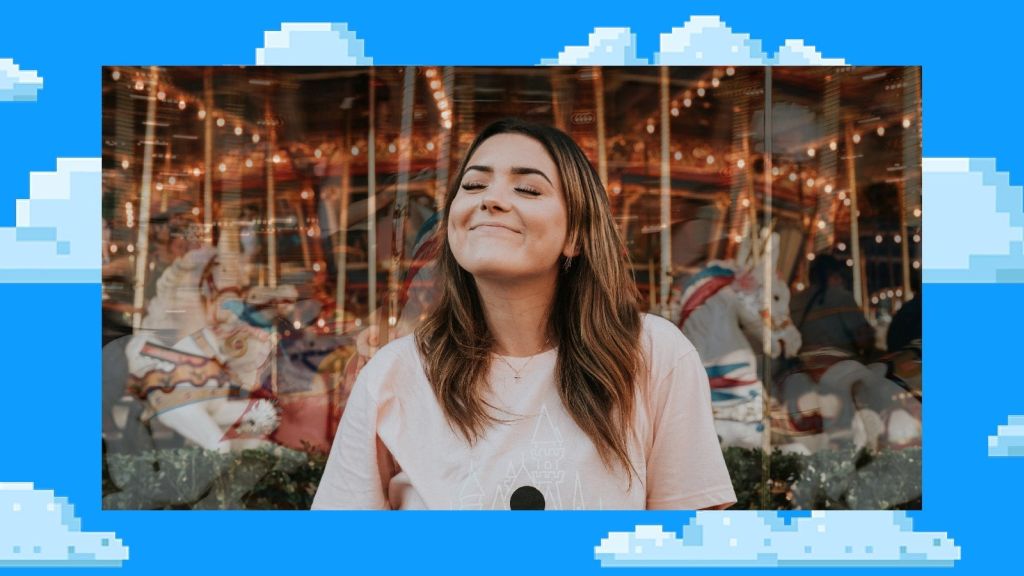 Illustrative photo of a person in from of a merry-go-round, smailing with their eyes closed