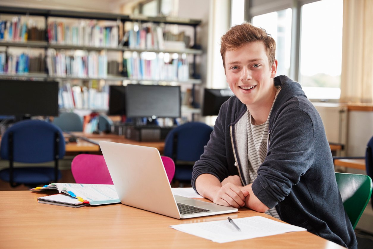 Illustrative image of a person sitting in front of a laptop in a library.
