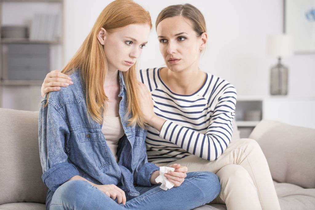 Illustrative image of two friends sitting and chatting outside a coffee shop.