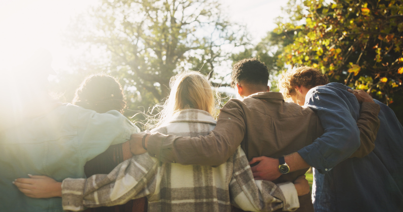 Illustrative image of a group of people, with their backs facing the camera, relaxing together in a leafy green setting.