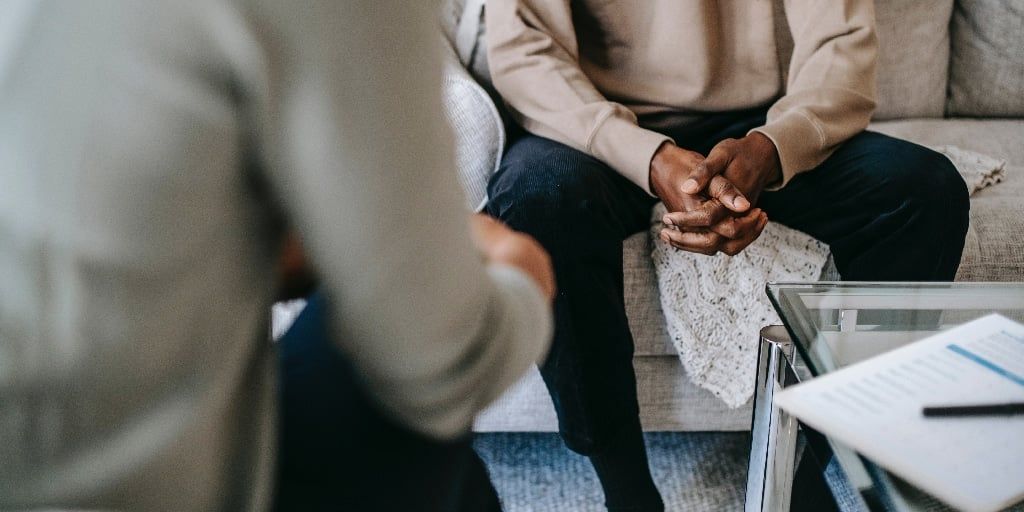 Illustrative image of a group of people, with their backs facing the camera, relaxing together in a leafy green setting.