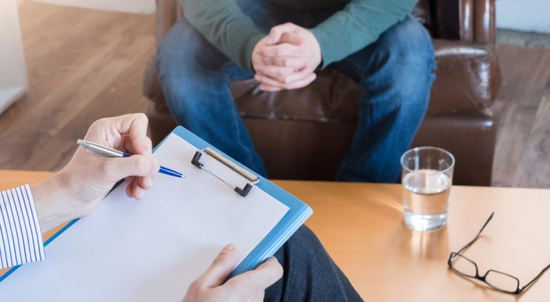 Illustrative image of a person sitting in front of another person with a clipboard.