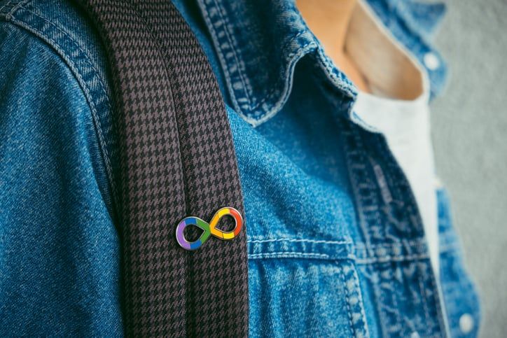 Illustrative image of a person wearing a colourful autistic spectrum logo badge.