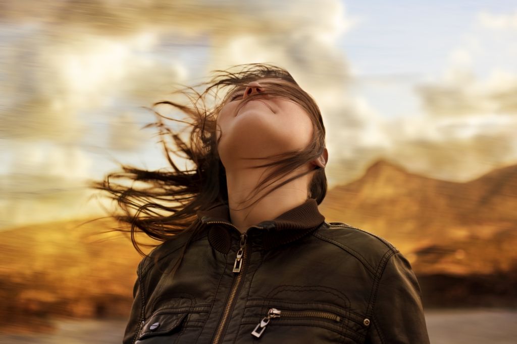 Illustrative image of a person with head tilted upwards and hair blowing in the wind.