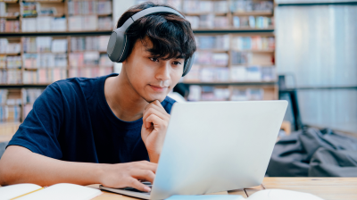 young person looking at their laptop in a library