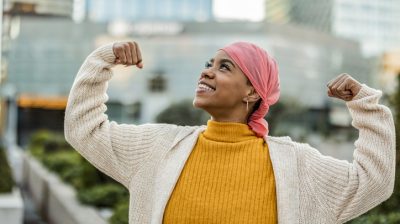 Illustrative image of a person smiling and raising both fists to celebrate their own strength.