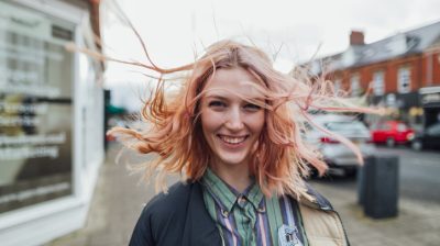 Illustrative image of a person smiling with hair blowing in the wind.