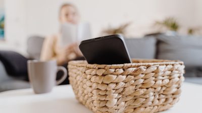 Illustrative image of a person reading while their phone is set aside in a basket.