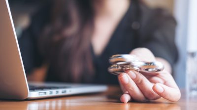 Illustrative image of a person using a laptop while playing with a fidget spinner on a wooden table.