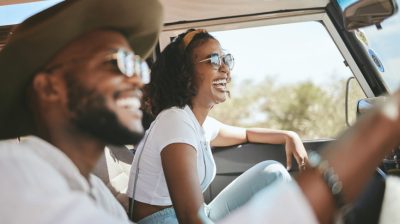 Illustrative image of a smiling couple in a car driving through the countryside.