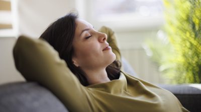 Illustrative image of a person relaxing on a sofa at home.