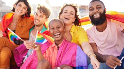 Illustrative image of a group of friends smiling and waving the rainbow flag.