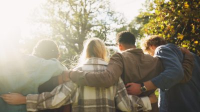 Illustrative photo of a group of people, with their backs facing the camera, relaxing together in a leafy green setting.