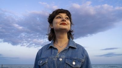 Illustrative image of a smiling person holding their head up high against a cloudy background.