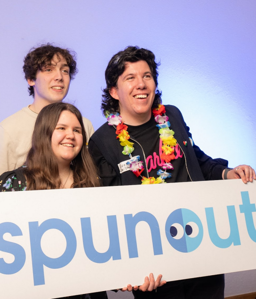 Three of spunout's volunteers holding a spunout logo sign