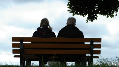 young woman and older man sitting together on a bench