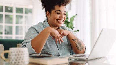 Smiling person video calling using laptop at home