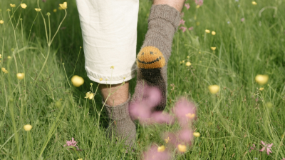 A person wearing socks with a smiling face on the heels walks away.