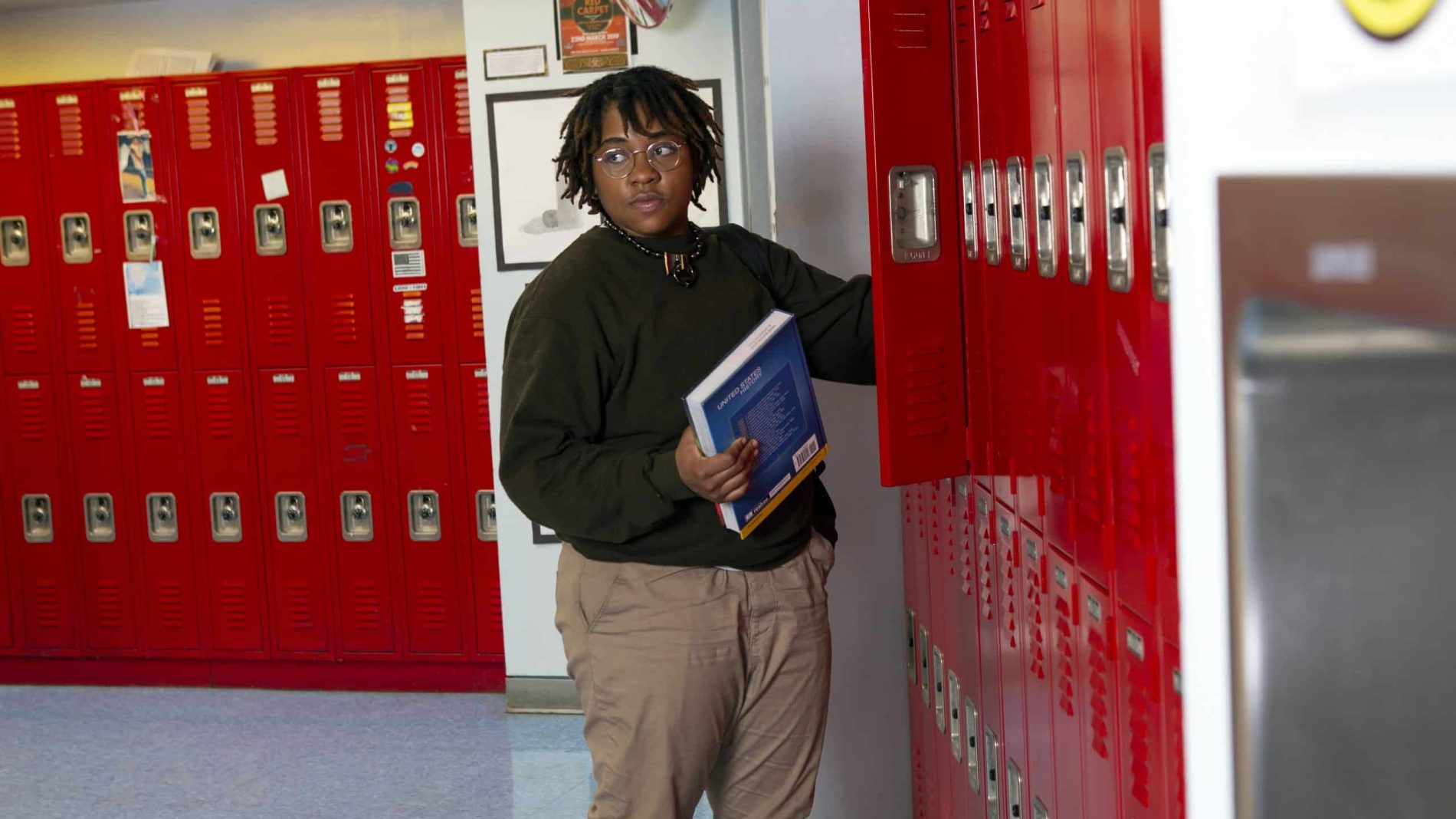 A non-binary student getting a book out of their locker
