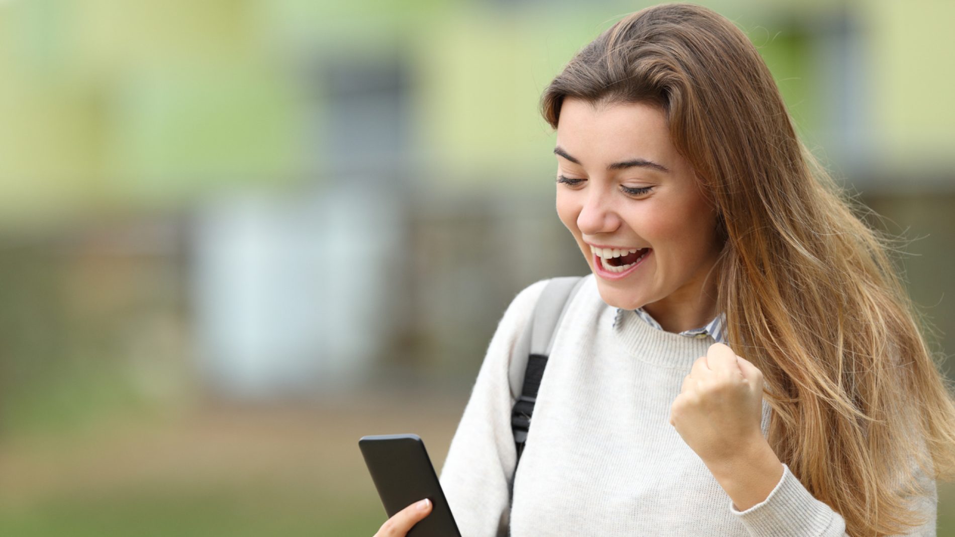 Excited student reading news on a smart phone