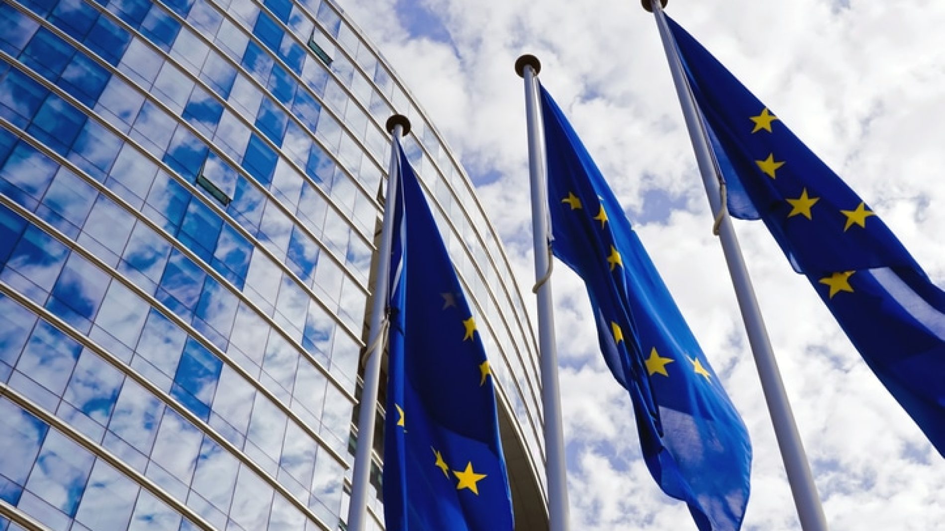 Three European Union flags outside the European Parliament building