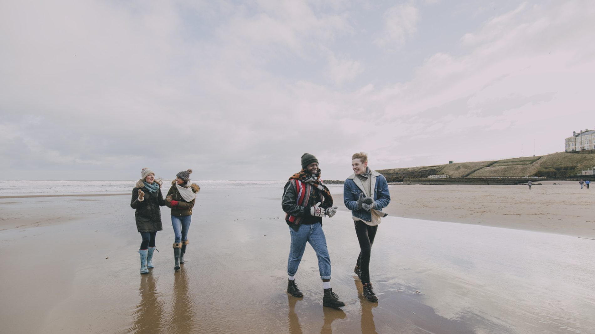A Group Of Friends Walk Along A Winter Beach